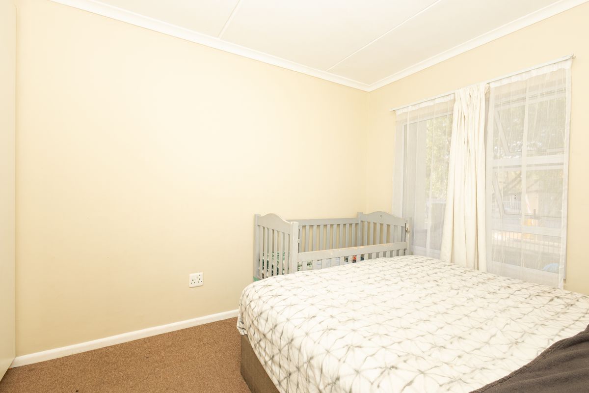 A standard bedroom featuring carpeted flooring, neutral wall finishes, and a window with natural light.