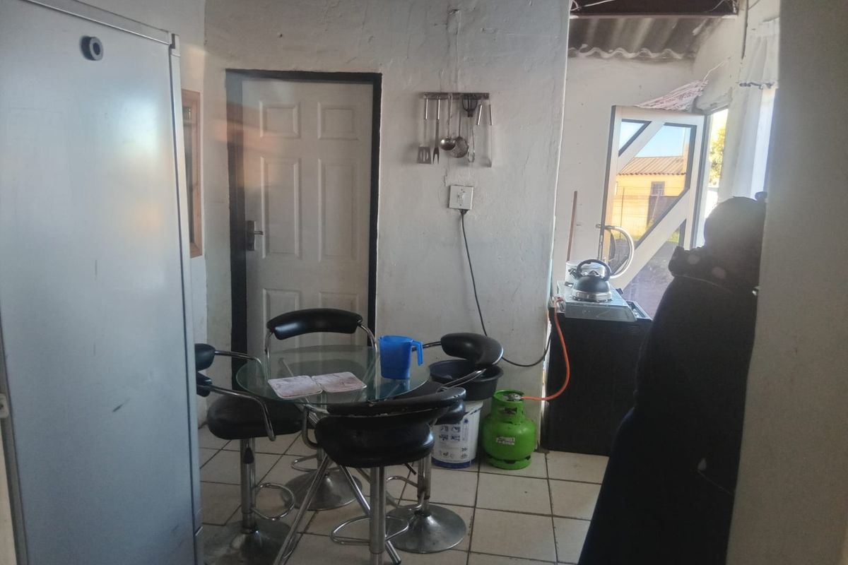 A small kitchen area featuring tiled flooring and basic utility connections, currently requiring significant cosmetic updates and finish improvements.