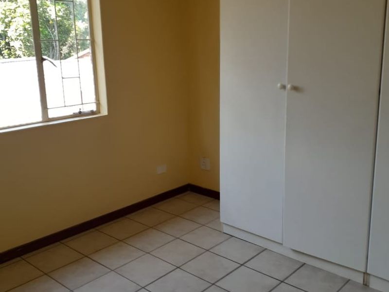 A clean, empty bedroom featuring neutral walls, tiled flooring, and built-in cupboards, offering a blank canvas for personalization.