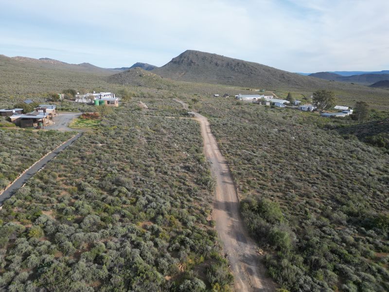 Aerial view of a rural farm property featuring multiple structures, gravel access roads, and expansive natural landscape.