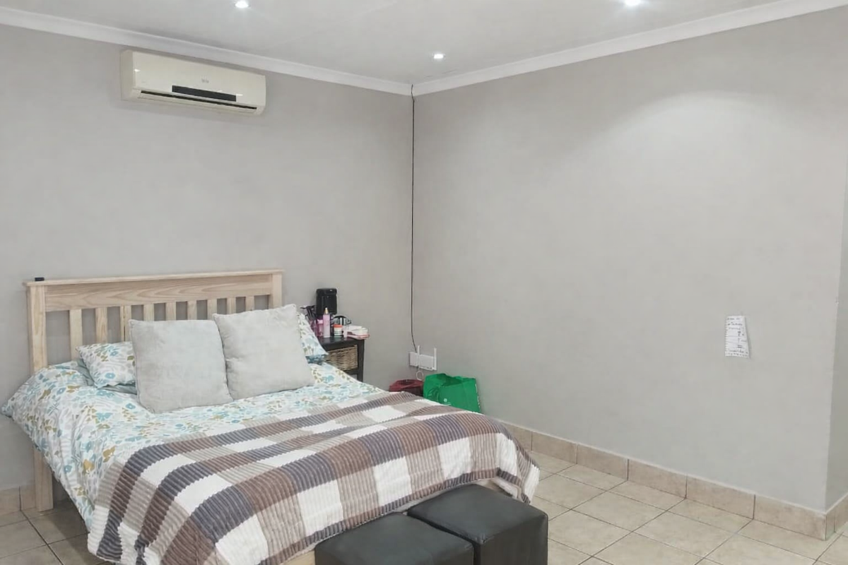 A bedroom featuring tiled flooring, recessed ceiling lighting, and a wall-mounted air conditioning unit.