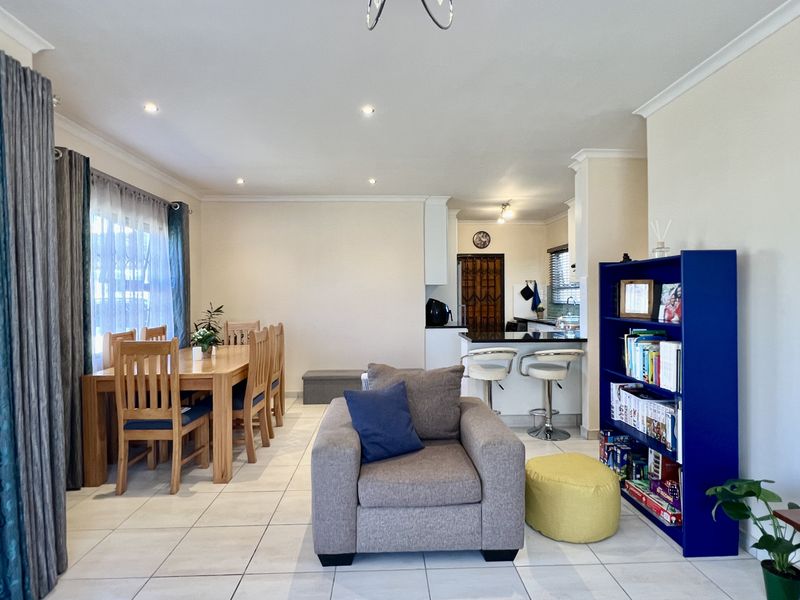Open-plan living and dining area featuring tiled flooring, recessed downlighting, and a breakfast bar connecting to the kitchen space.