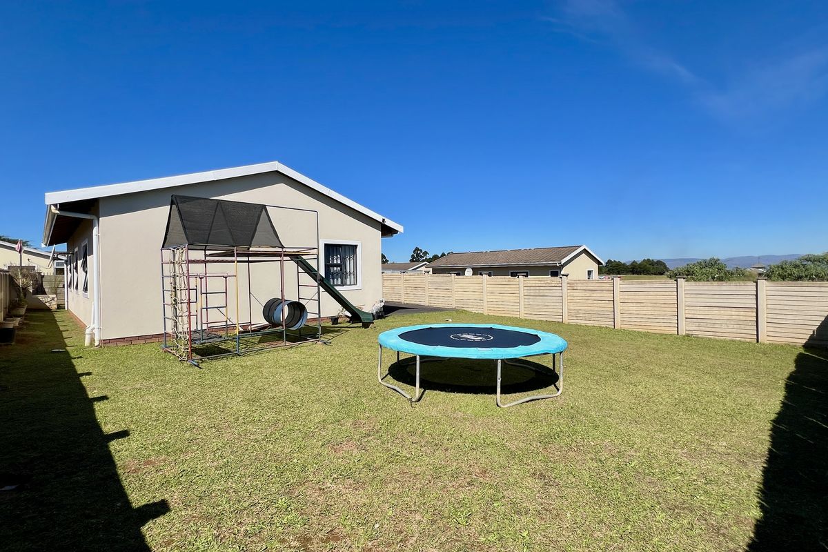A spacious rear garden featuring a well-maintained lawn, enclosed by high perimeter walls, providing a private outdoor area for the property.