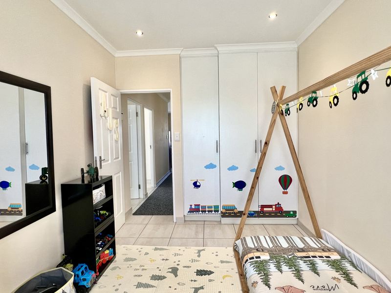A bedroom featuring built-in floor-to-ceiling wardrobes, tiled flooring, and recessed ceiling lighting, providing a functional and well-maintained living space.