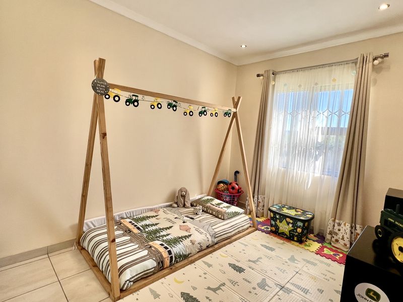 A well-maintained bedroom featuring neutral wall tones, tiled flooring, built-in cupboards, and recessed ceiling lighting.