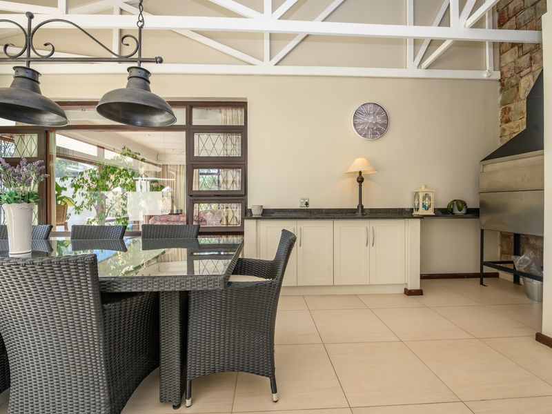 Covered patio area featuring a built-in braai, stone feature wall, exposed white roof trusses, and built-in cabinetry with granite countertops.
