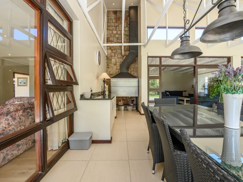 Spacious covered patio featuring a built-in braai, stone feature wall, and exposed roof trusses, perfect for outdoor entertaining and dining.
