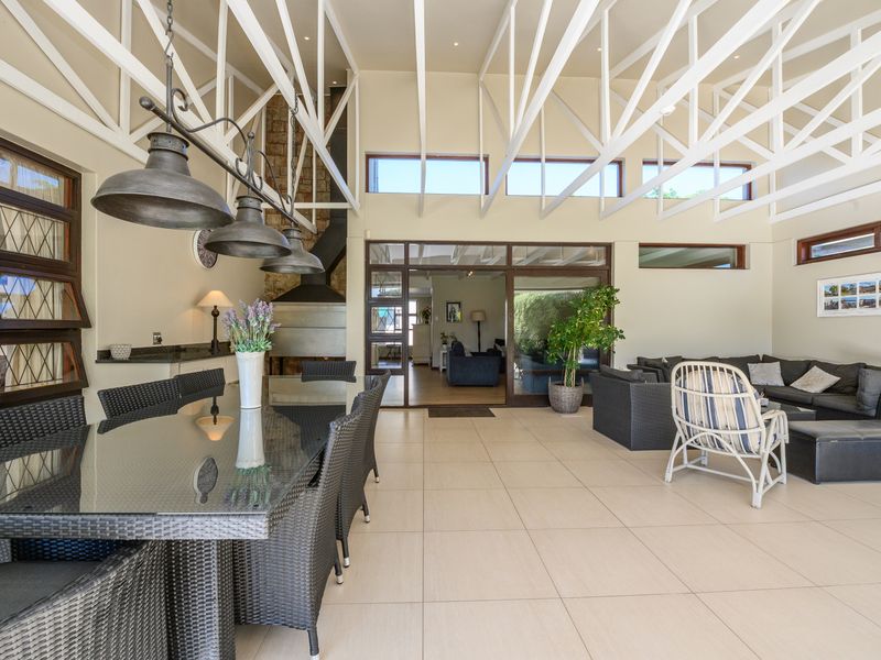 Spacious covered patio featuring high vaulted ceilings with exposed white trusses, a built-in fireplace with stone detailing, and large sliding doors to the interior.