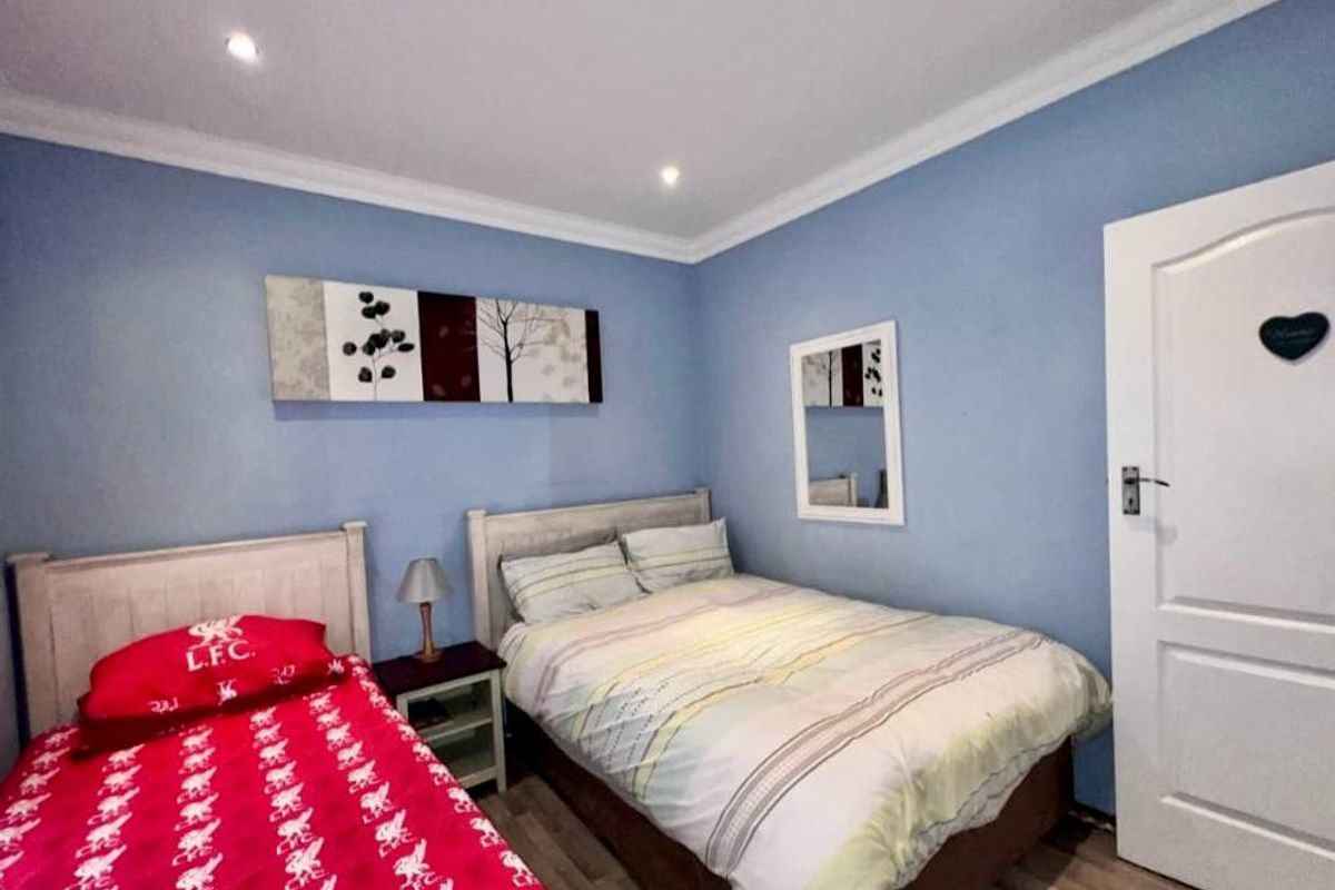 A functional bedroom featuring laminate flooring, recessed downlighting, and decorative coving, providing a comfortable space for rest.