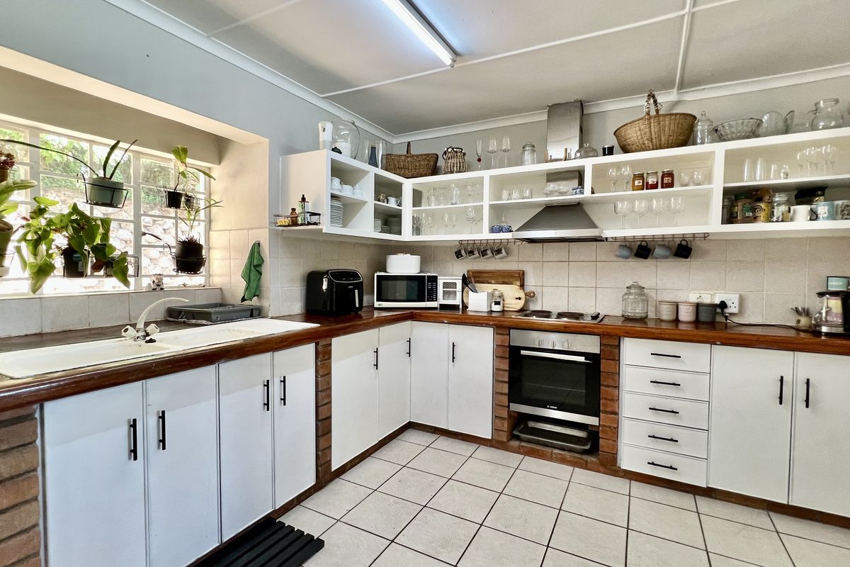 A functional kitchen featuring white cabinetry, wooden countertops, brick accents, tiled flooring, and built-in appliances with ample open shelving for storage.
