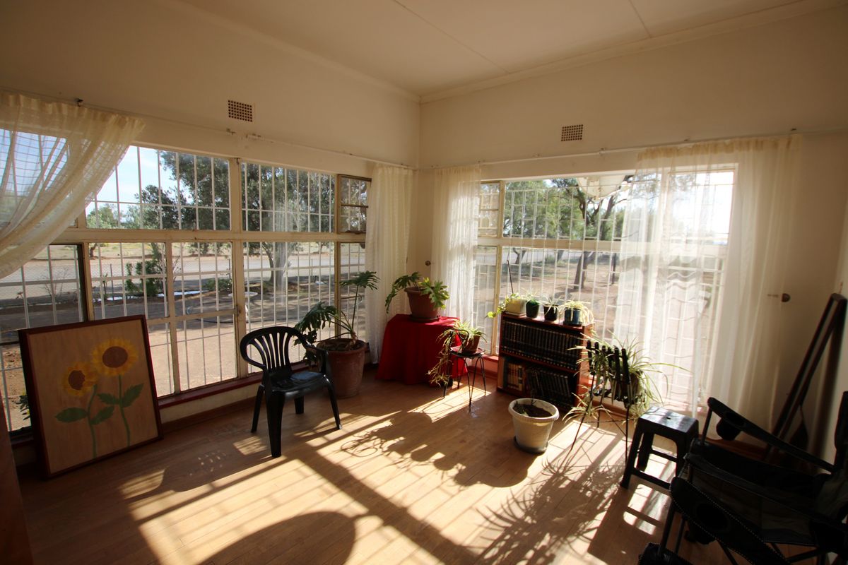 A sunlit living area featuring extensive steel-framed windows providing ample natural light and views of the surrounding property.