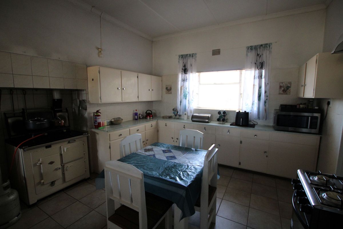 A dated kitchen featuring original built-in cabinetry, tiled flooring, and a vintage stove, offering significant potential for a modern renovation.