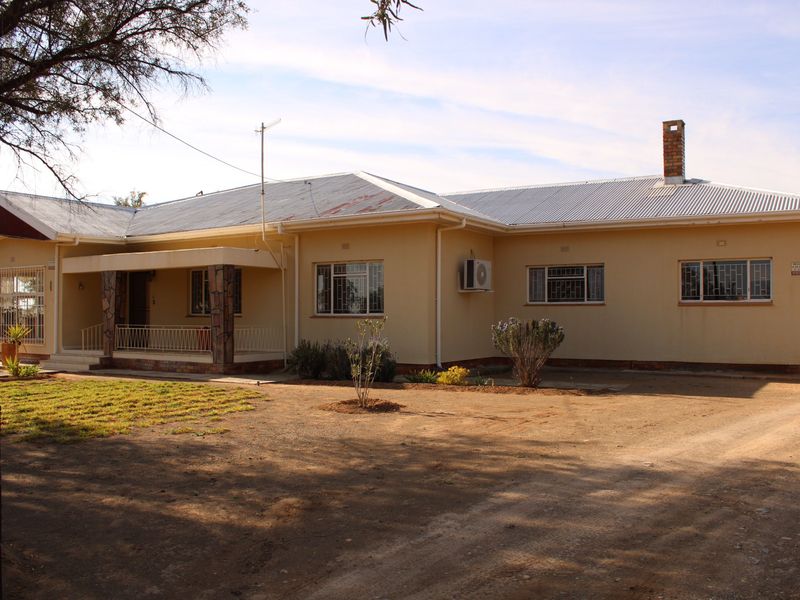 Single-story residential house featuring a corrugated metal roof, brick chimney, and a covered front porch with stone-clad pillars.