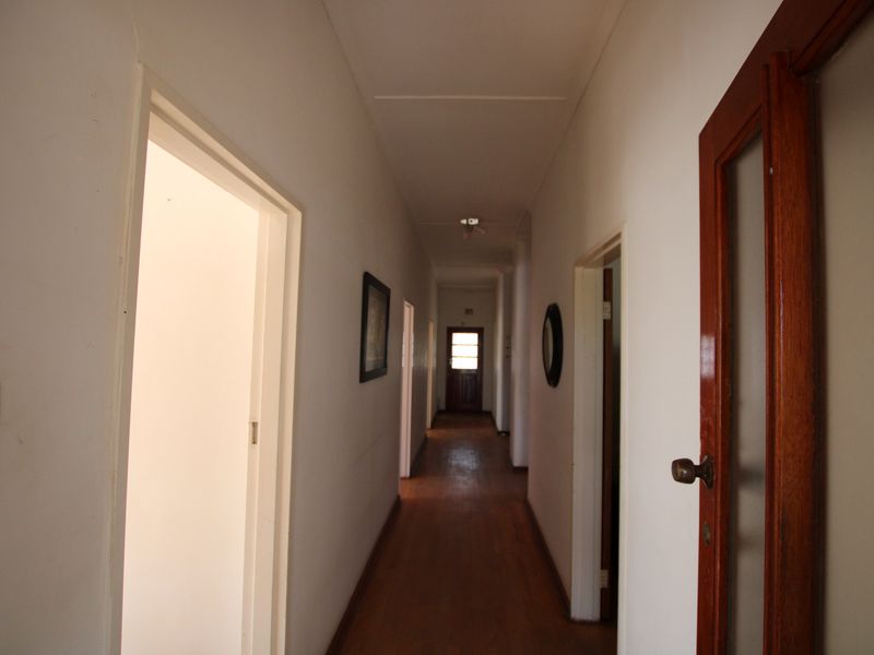 A long interior hallway featuring timber flooring and multiple doorways leading to various rooms, providing access throughout the home.