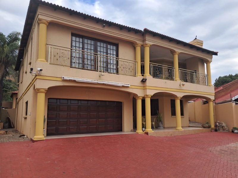 A two-story residential property featuring a double garage, upper-level balcony with wrought iron railings, and classic column detailing on the front facade.