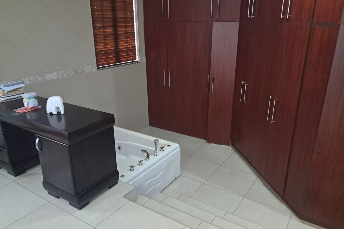 A unique bathroom featuring a sunken bathtub, extensive built-in wooden cabinetry for storage, and neutral floor tiling.