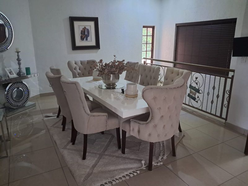 A well-lit dining room featuring tiled flooring, a decorative wrought iron balustrade, and venetian blinds, creating a comfortable space for family meals.