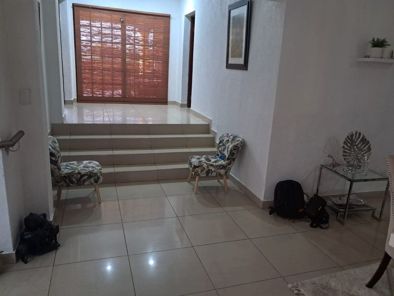 A living area featuring tiled flooring, a raised platform section, and a sliding glass door leading to an outdoor space.