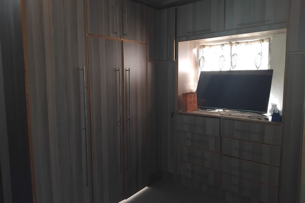 A bedroom featuring extensive built-in cabinetry with integrated drawers and storage, finished in a modern wood-grain laminate.