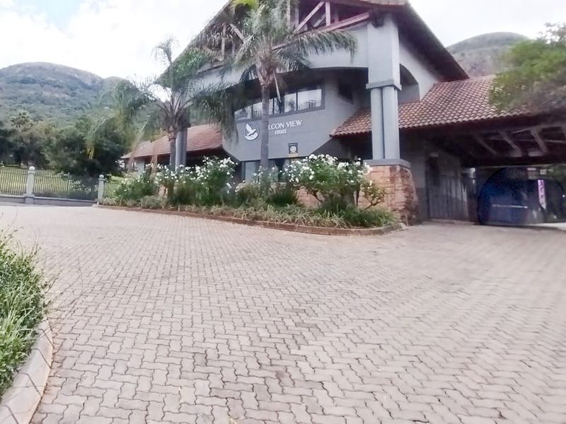 Front elevation of the Falcon View Estate entrance, featuring a paved driveway, stone-clad facade, and tiled roof structure.