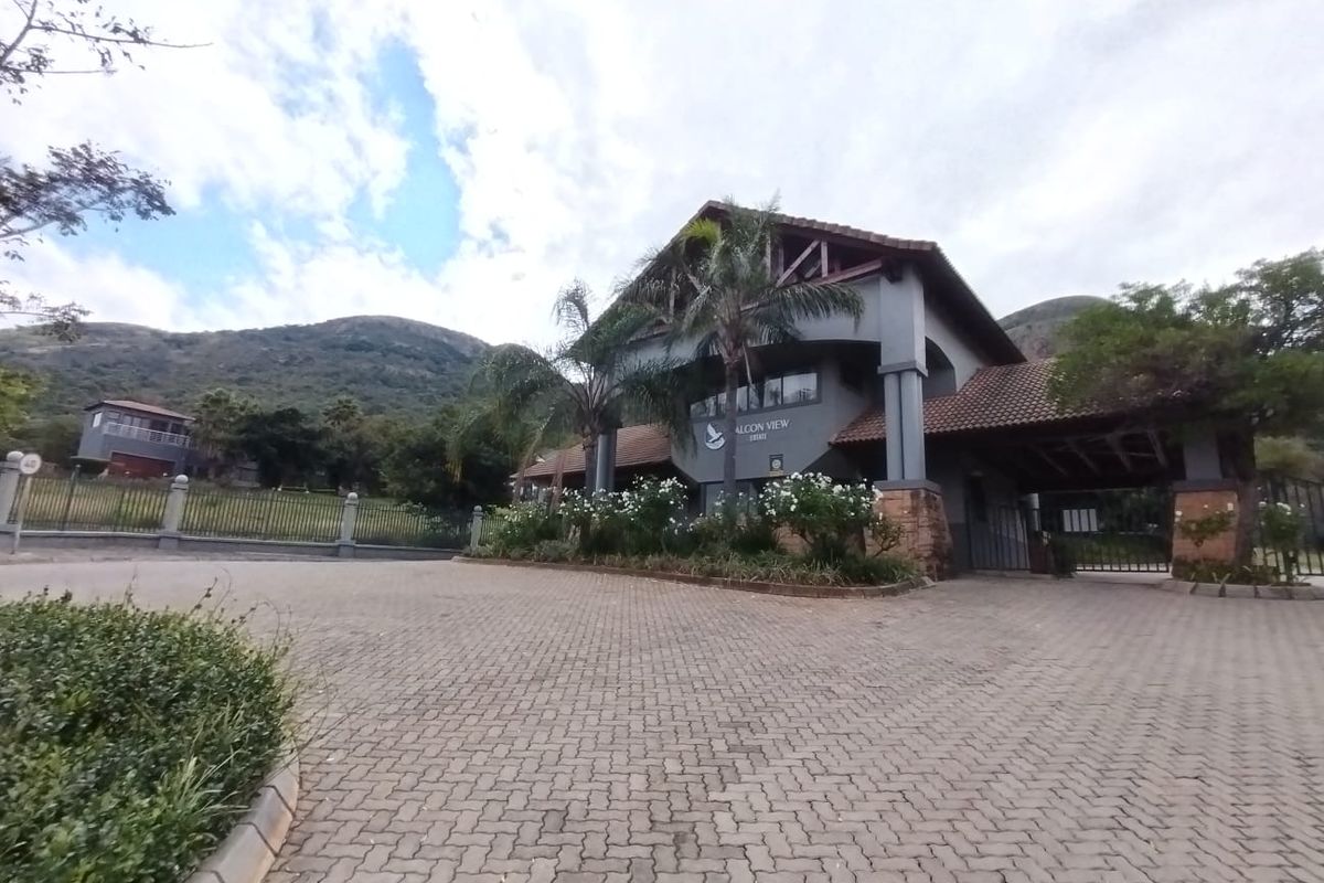 The entrance to Falcon View Estate featuring a paved driveway, secure gate access, and a prominent architectural entrance structure.