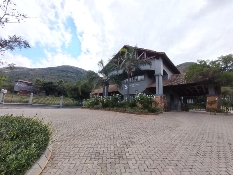 The entrance to Falcon View Estate featuring a paved driveway, secure gate access, and a prominent architectural entrance structure.