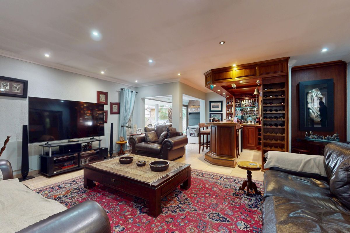 Spacious living room featuring a custom built-in wooden bar with integrated wine storage, recessed lighting, and tiled flooring throughout.