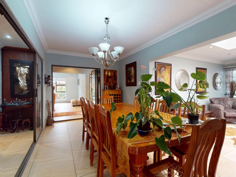 Spacious open-plan dining area featuring tiled floors, crown molding, and a built-in wine display cabinet, seamlessly connecting to adjacent living spaces.