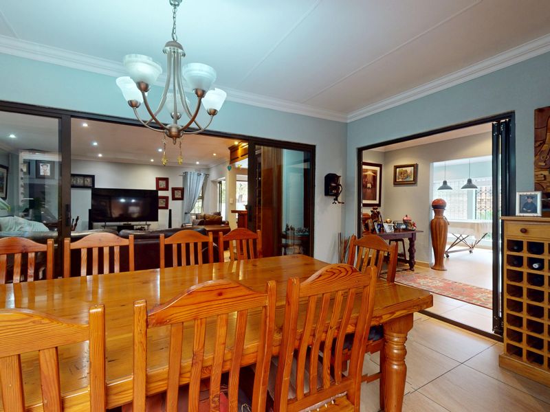 Spacious dining room featuring tiled flooring, crown molding, and large sliding glass doors that provide an open flow to the adjacent living areas.