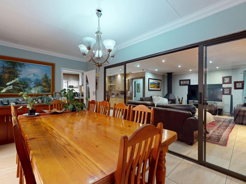 Dining room featuring tiled flooring, cove cornice, and a chandelier, with sliding glass doors providing a view into the adjacent living area.