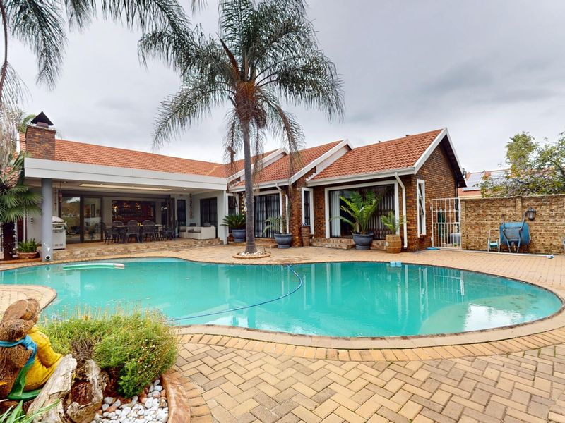 Spacious outdoor entertainment area featuring a large swimming pool, brick-paved patio, and a covered patio space attached to the main residence.