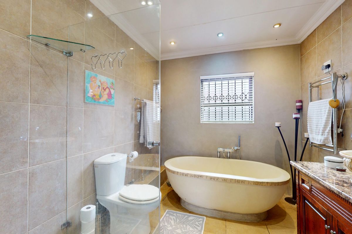 A well-appointed bathroom featuring a freestanding bathtub, glass-enclosed shower, vanity with stone countertop, and a heated towel rail.