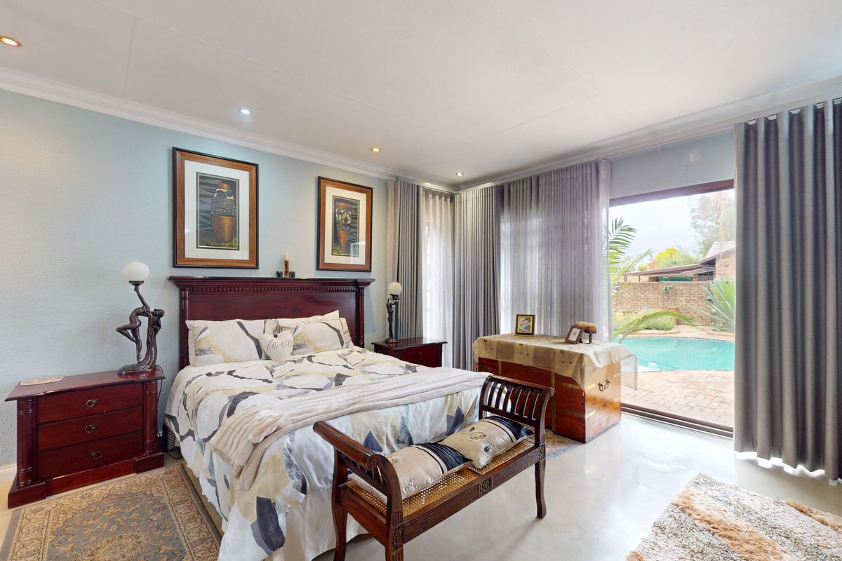 Spacious bedroom featuring tiled flooring, recessed lighting, and large sliding glass doors providing direct access to the outdoor pool area.