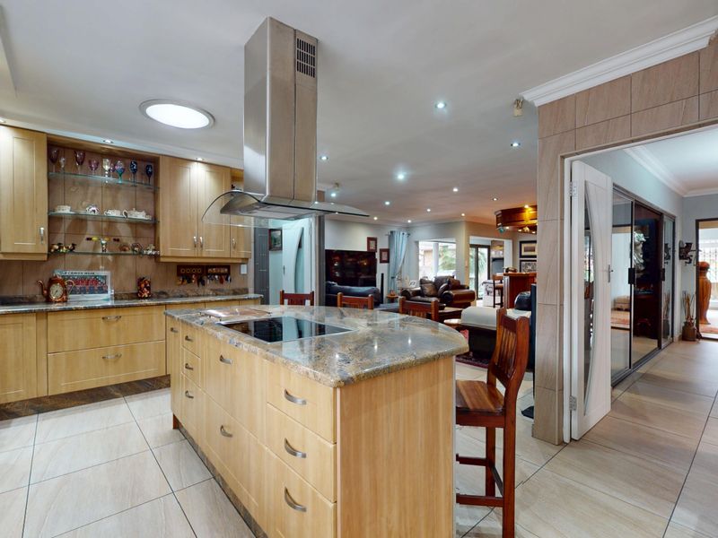 Spacious open-plan kitchen featuring a central island with granite countertops, built-in appliances, and modern recessed lighting, flowing into the adjacent living area.