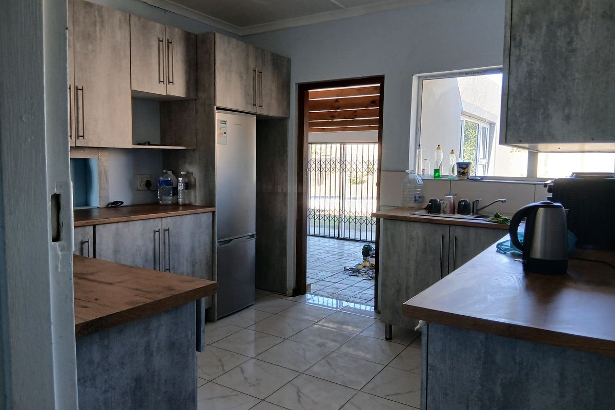 A functional kitchen featuring modern grey cabinetry, wood-look laminate countertops, tiled flooring, and direct access to an outdoor patio area.