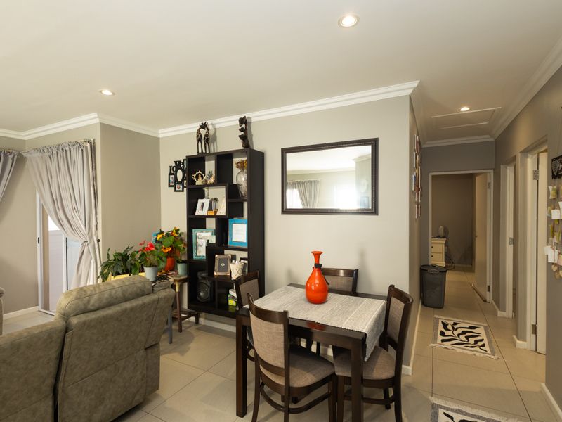 A well-maintained living area featuring neutral wall tones, tiled flooring, recessed downlighting, and decorative crown molding throughout the space.