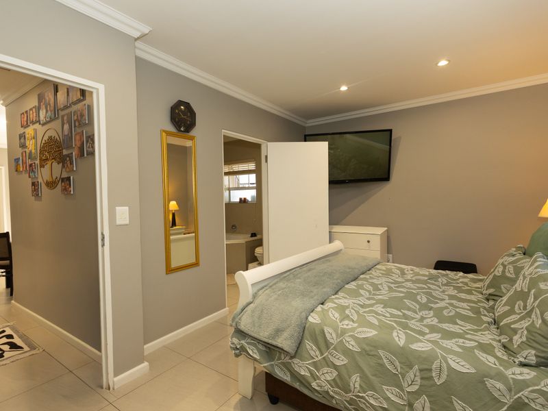 A well-maintained bedroom featuring tiled flooring, recessed downlighting, and direct access to an en-suite bathroom.