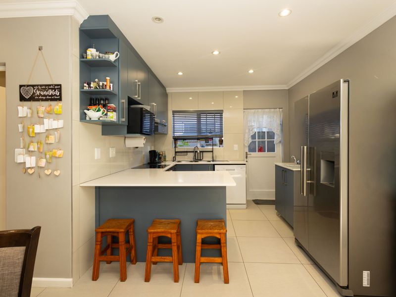 Modern kitchen featuring blue cabinetry, white quartz countertops, tiled flooring, and recessed lighting, offering a clean and functional workspace.