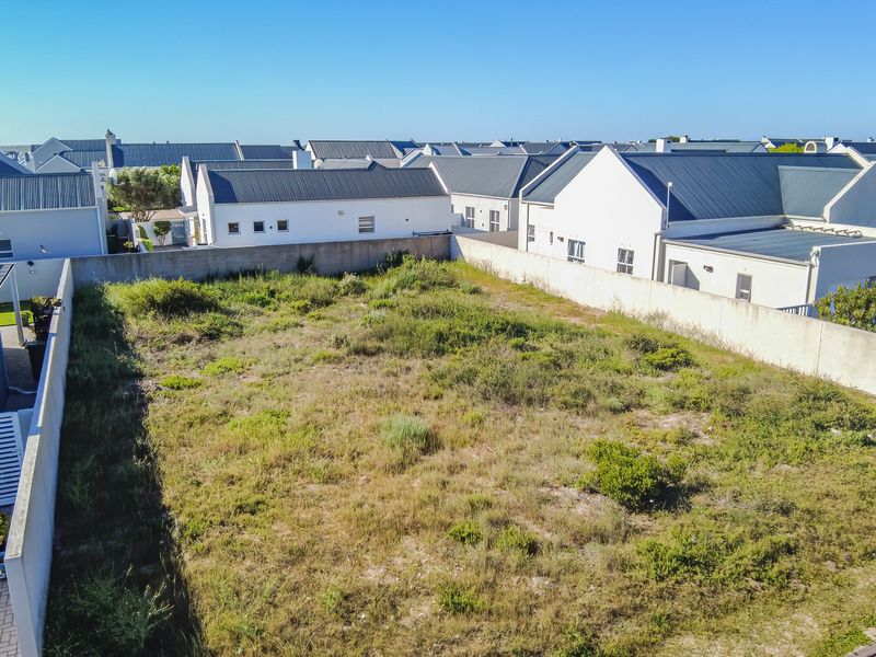 An aerial view of a vacant residential plot enclosed by perimeter boundary walls, situated within a developed residential estate.