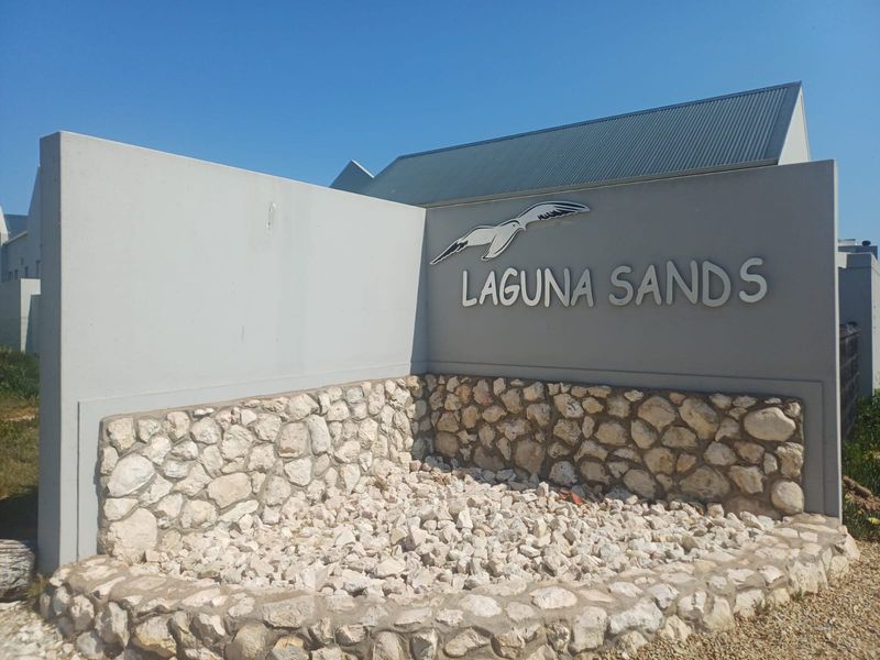 Entrance signage for Laguna Sands featuring a stone-clad concrete wall and modern architectural design.