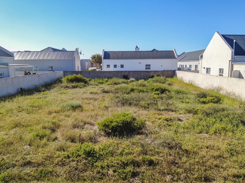 A vacant residential plot of land enclosed by boundary walls, situated in a developed neighborhood.
