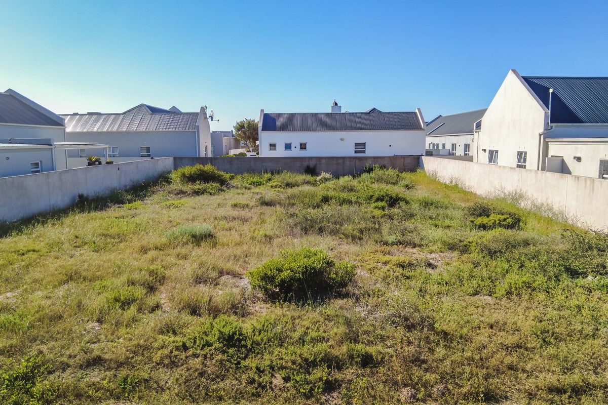 A vacant residential plot of land enclosed by boundary walls, situated in a developed neighborhood.