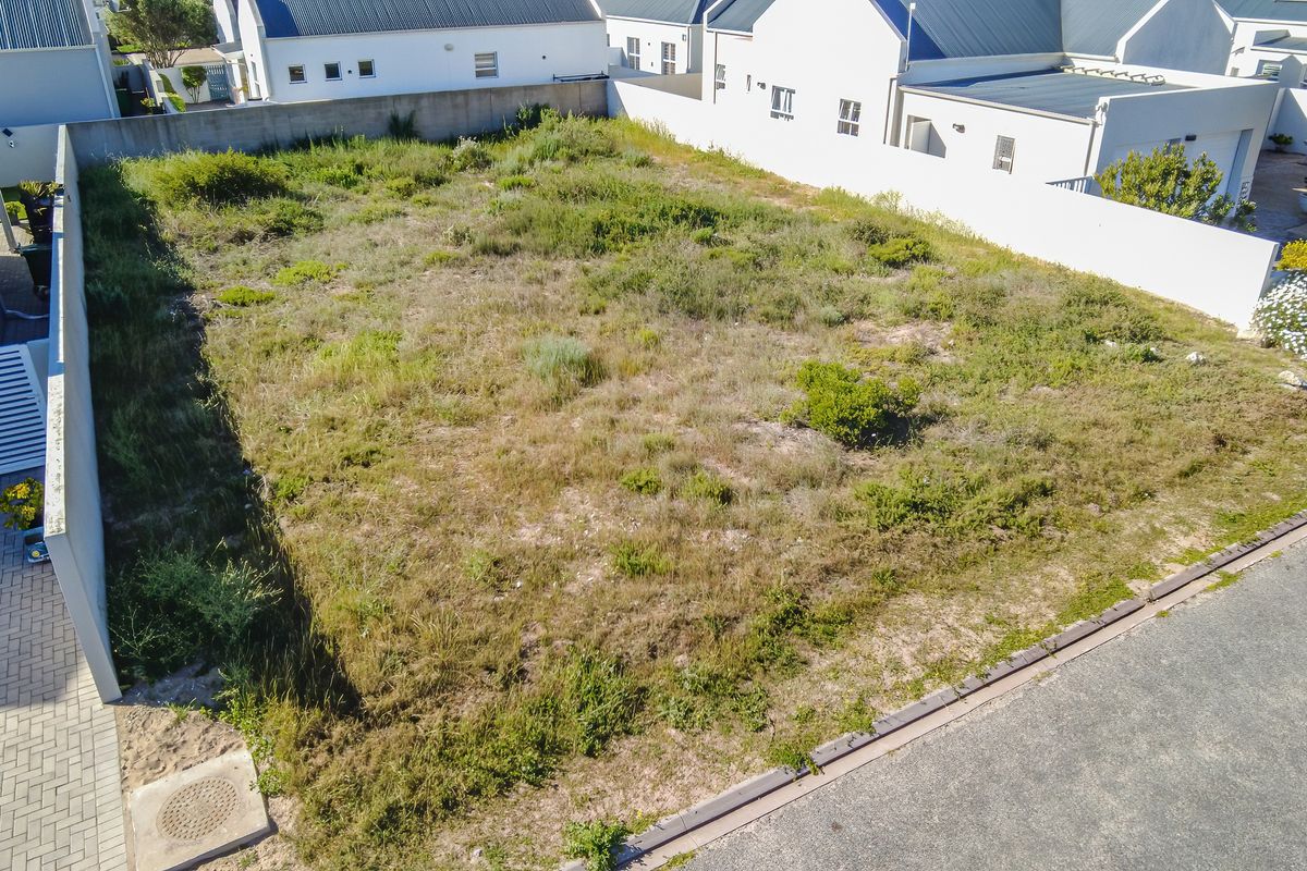 An aerial view of a vacant residential plot featuring boundary walls and direct street access, ready for development.