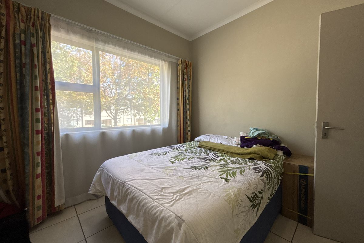 A standard bedroom featuring tiled flooring and a large window providing natural light.