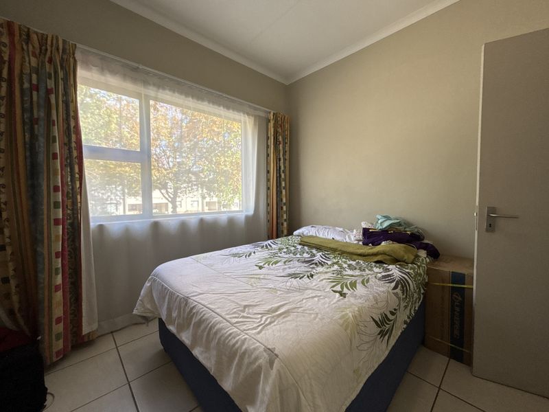 A standard bedroom featuring tiled flooring and a large window providing natural light.