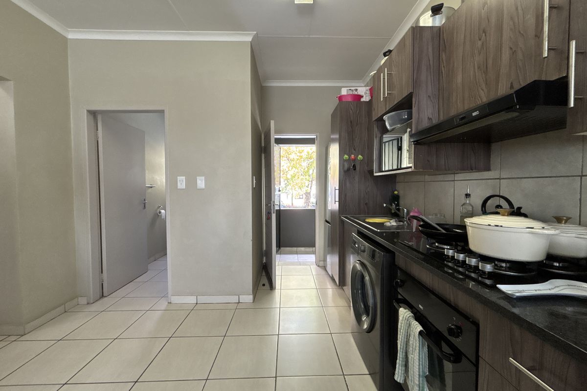 Functional kitchen featuring dark wood cabinetry, granite countertops, integrated oven, gas hob, and tiled flooring with direct access to an exterior area.