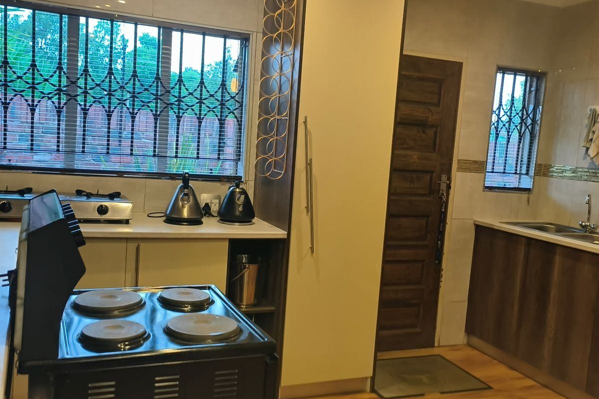 A functional kitchen featuring built-in cabinetry, a double sink, tiled backsplash, and security bars on the windows.