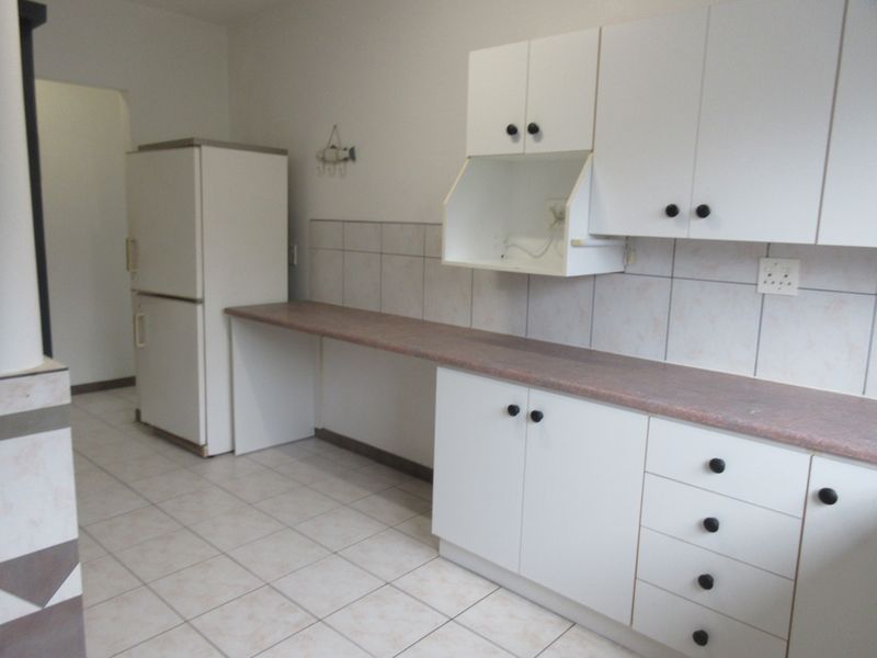 A functional kitchen featuring white cabinetry, laminate countertops, tiled backsplash, and ceramic floor tiles, offering a clean and practical workspace.