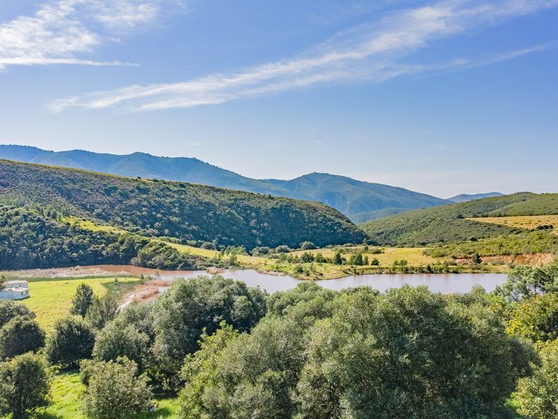 Scenic landscape view featuring a natural dam, rolling hills, and expansive mountain vistas on this farm property.