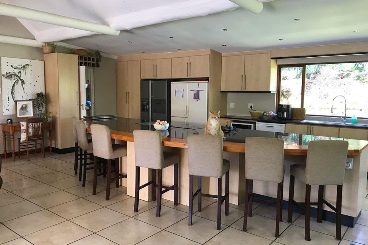 Spacious kitchen featuring light wood cabinetry, a large island with a stone countertop, tiled flooring, and ample natural light from the window.
